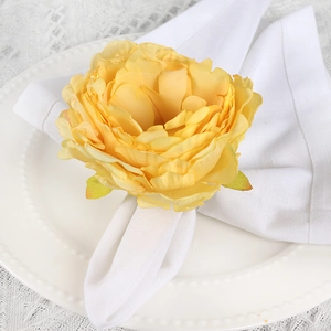 Elegant yellow artificial rose napkin ring on white fabric for wedding table decor
