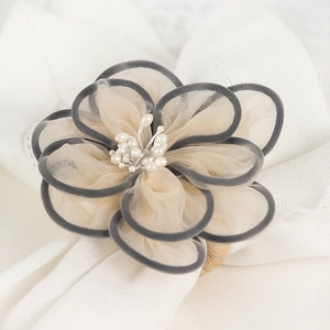 Elegant mesh flower napkin ring with black edges and pearls on woven rustic base