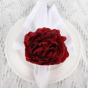 Detailed close-up of a burgundy fabric rose napkin ring on a white beaded ceramic plate