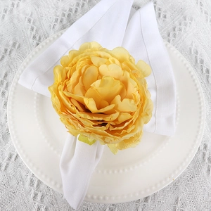 Top view of yellow artificial rose napkin ring on white plate with lace tablecloth