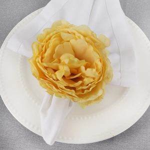 Top view of a bright yellow fabric rose napkin ring placed on a white porcelain plate