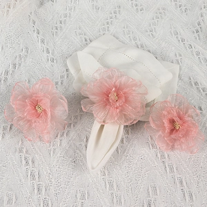 Pink mesh flower napkin rings set on white lace tablecloth for festive table setting