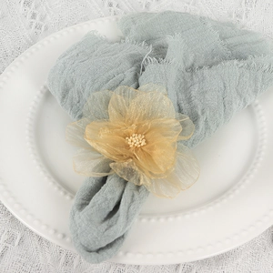 Champagne mesh flower napkin ring with pearls on a blue gauze napkin and lace tablecloth