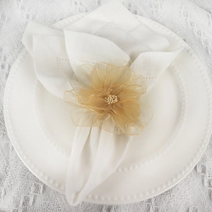 Champagne gold mesh flower napkin ring with pearls on a white plate and lace tablecloth