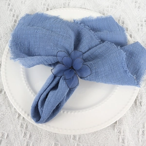 Detailed view of a blue mesh flower napkin ring on a white ceramic pearl plate