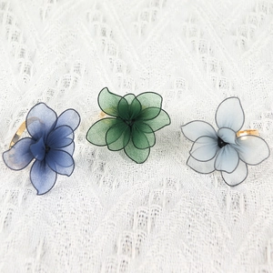Detailed view of 3D mesh flower napkin rings in dark blue, green, and blue-gray hues
