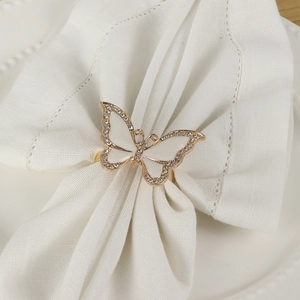Detailed view of elegant gold butterfly napkin ring with rhinestones on a white ceramic plate
