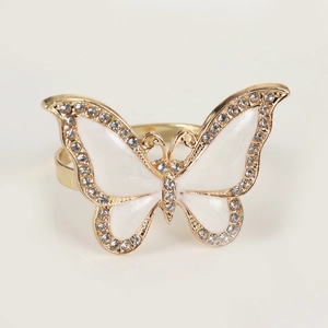 Macro shot of gold butterfly napkin ring featuring white enamel wings and pavé crystals
