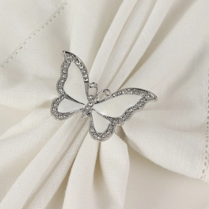Close-up of white enamel butterfly napkin ring with rhinestones on a white linen napkin