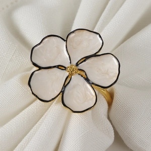 Detail of five-petal floral napkin ring with white enamel petals and gold center