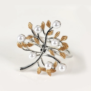 Macro shot of silver metal napkin ring featuring gold leaves and white pearls