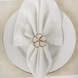 Top view of five-petal flower napkin ring with white enamel and golden center detail