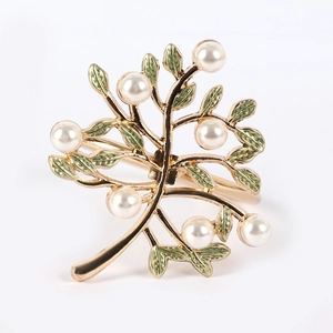 Detail of golden money tree napkin ring with green enamel leaves and white pearls