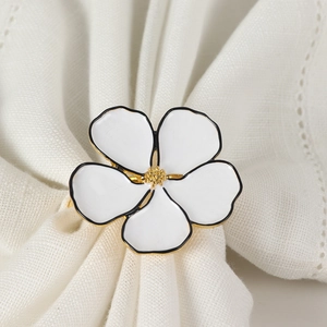 Elegant white five-petal flower napkin ring with gold stamens on a linen napkin
