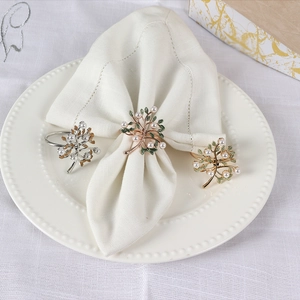 Detailed view of tree-shaped metal napkin rings with colorful enamel leaves and pearls