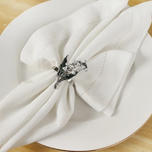 Rond de serviette élégant avec fleurs de muguet et feuilles vertes sur base argentée