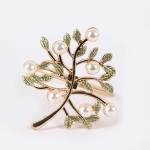 Detailed view of golden tree branch napkin ring with green leaves and white pearls