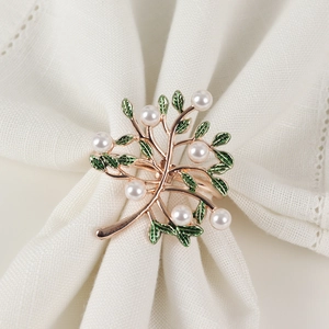 Rose gold tree napkin ring with white pearls and green leaves on white linen