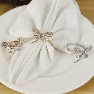 Detailed view of silver dragonfly napkin ring with sparkling rhinestones on white linens