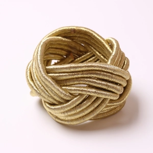 Close-up of a handmade golden woven rope napkin ring with intricate knot detailing