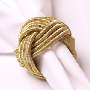 Macro shot of hand-woven champagne gold knot napkin ring on a white fabric napkin