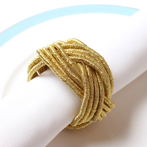 Macro detail of hand-woven gold metal wire napkin ring on a white plate