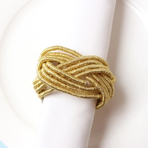 Detail of hand-woven gold rope napkin ring on white linen napkin for table setting