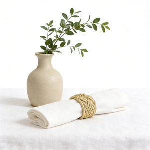 Elegant gold woven knot napkin ring on a white linen napkin for formal table setting