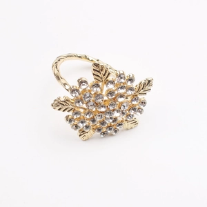 Golden leaf napkin ring with sparkling crystal flower cluster on a white background