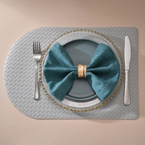 Overhead view of rose gold leaf napkin ring on blue fabric with woven placemat