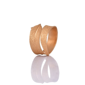 Elegant rose gold leaf napkin ring with textured wrap design on reflective white surface