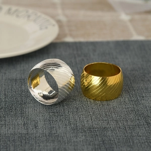 Close-up of gold and silver napkin rings featuring diagonal matte metal texture