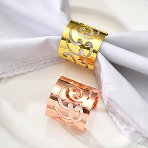 Elegant gold and rose gold cutout scroll pattern metal napkin rings on white ceramic plate