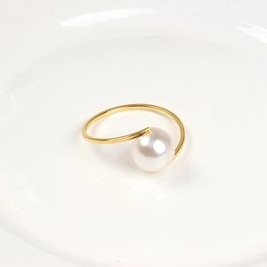 Detailed view of elegant gold napkin ring featuring a large white pearl on a ceramic plate