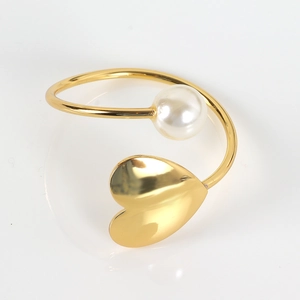 Close-up of golden napkin ring featuring a large white pearl and heart-shaped charm