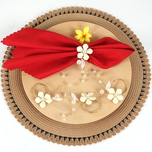 Detailed macro view of white enamel flower napkin ring with elegant pearl tassels and leaf deco