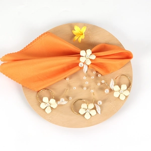 Set of three white flower napkin rings with pearls and gold bands for table decoration