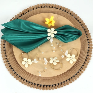 Detail of elegant gold napkin rings with white enamel flowers and pearl tassels