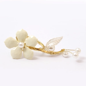 Detail of white flower napkin ring with pearls and gold wire base on white background