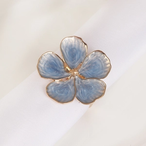 Portatovagliolo con petali in smalto blu e bordo dorato su tovagliolo di stoffa