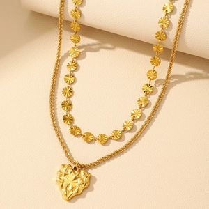 Detail of double-layered gold necklace with sun-burst discs and crumpled heart pendant