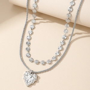 Double-layered silver necklace featuring a textured heart pendant and radiant discs charms