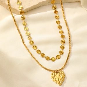 Close-up of gold double-layer necklace with sunburst disks and hammered heart pendant