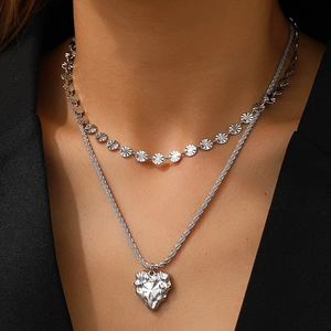 Detail of silver double-layered necklace featuring sunburst discs and a wrinkled heart pendant