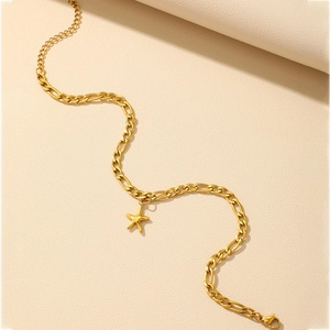 Detail of a gold starfish pendant on a Figaro chain against a beige leather background