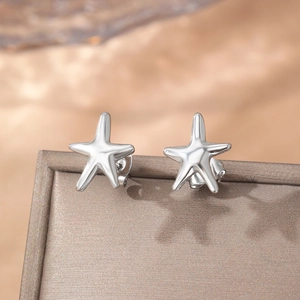 Boucles d'oreilles étoiles de mer en argent poli sur un fond élégant en satin