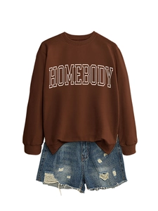 Detail of dark brown oversized sweatshirt with Homebody print and ripped denim shorts
