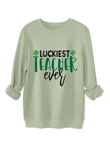 Close-up of Luckiest Teacher Ever print with shamrocks on a green crewneck sweatshirt