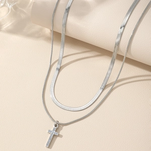 Double-layered silver necklace featuring a sparkling rhinestone cross pendant and snake chain