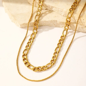 Détail d'un collier à double rang de chaîne Figaro dorée et fine maille texturée